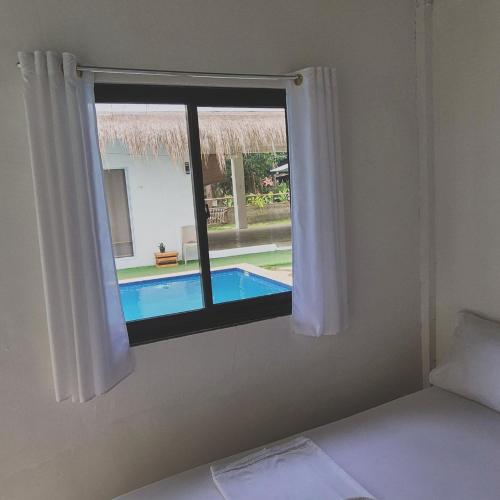 a bedroom with a view of a swimming pool through a window at Camotes Hostel Resort in Camotes Islands
