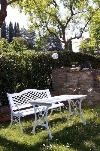 a white bench sitting in the grass in a yard at Agriturismo Villino del Grillo in San Gimignano