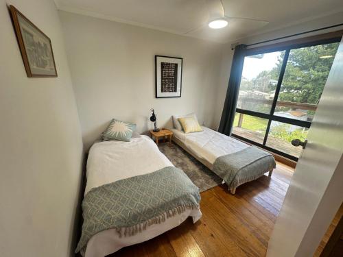 a bedroom with two beds and a window at Saturn Sands - 30 Saturn Parade in Venus Bay