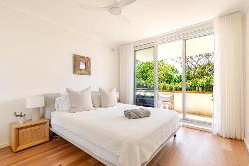 a white bedroom with a bed and a large window at Stylish and perfectly located Bondi Beach hideaway in Sydney