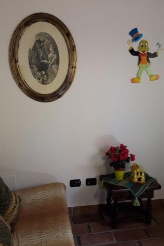 a picture hanging on a wall with a table and a shelf at Agriturismo Villino del Grillo in San Gimignano