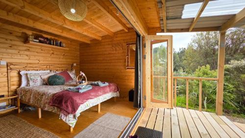 Upper PapamoaにあるFantail Point Glamping Cabinの木造キャビン内のベッド1台が備わるベッドルーム1室を利用します。