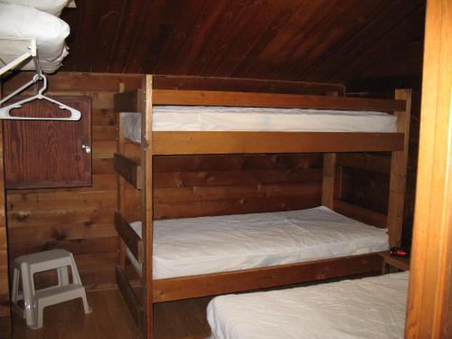 2 stapelbedden in een kamer met houten wanden bij Forest Lake Camping Resort Cabin 18 in Freewood Acres