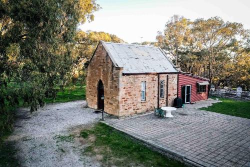 a small red brick building in a field at Clare Valley Cabins in Clare