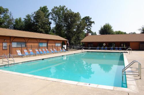 une grande piscine avec des chaises et un bâtiment dans l'établissement Forest Lake Camping Resort Cabin 18, à Freewood Acres