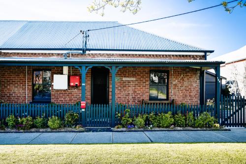 a brick house with a blue fence in front of it at Olive Cottage Rankin in Bathurst