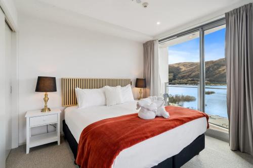 a hotel room with a bed with a teddy bear on it at Sunlit Serenity Lakefront Apartment in Frankton