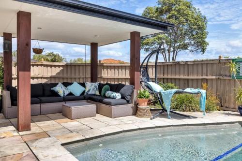 a patio with a couch next to a swimming pool at Beautiful Family House with Pool and BBQ in Gold Coast