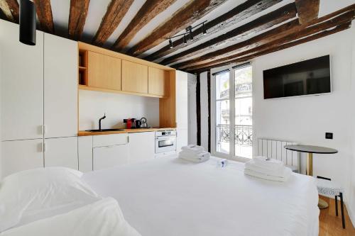 パリにあるQuiet studio for 2 people - Le Maraisの大きなベッドとテレビのある白い寝室