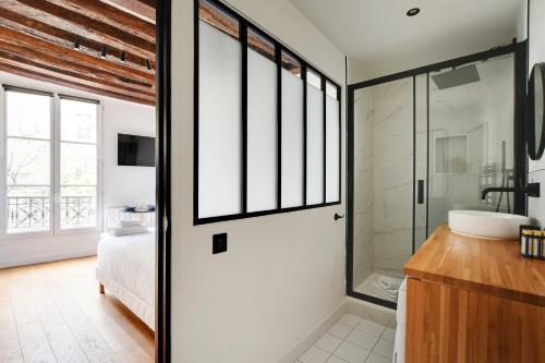 パリにあるQuiet studio for 2 people - Le Maraisのベッドルーム1室(ベッド1台付)、ガラスドア付きのバスルーム1室が備わります。