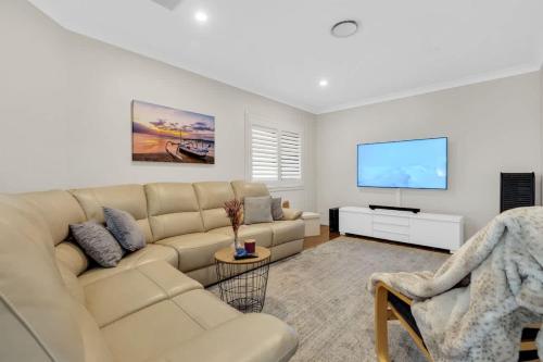 a living room with a couch and a flat screen tv at Beautiful Family House with Pool and BBQ in Gold Coast