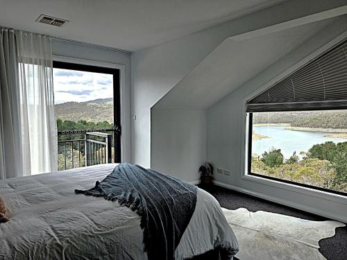 a bedroom with a bed and a large window with a view at Lake Kami Retreat - Jindabyne in Jindabyne