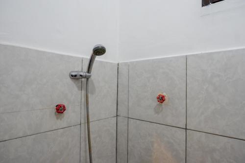 a shower with a shower head in a bathroom at RedDoorz Syariah @ Hotel Wisma Indonesia Kendari in Kendari