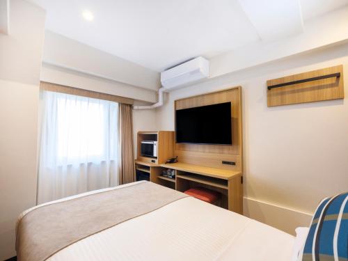 a hotel room with a bed and a tv at HOTEL MYSTAYS Higashi Jujo in Tokyo
