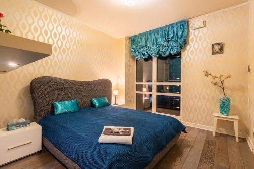 a bedroom with a blue bed and a window at PlatinumTowers! PRIVAT JACCUZI! PANORAMIC CITY VIEW from 14 Floor! LOGGIA! PARKING! 66m2! 2 ROOMS in Warsaw