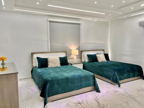 two beds in a white room with green sheets at FYV Beach Villas in San Juan