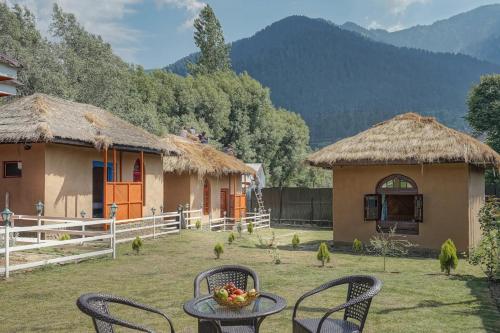 a table and chairs in front of two huts at Kulube cottages and restaurant in Kijapāra