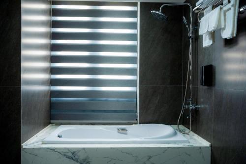 une baignoire blanche dans une salle de bain avec une fenêtre dans l'établissement Lumi Sky Hotel - by BAY LUXURY, à Hà Ðông