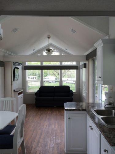 a kitchen and living room with a black couch at Circle M Camping Resort Loft Park Model in Wabank