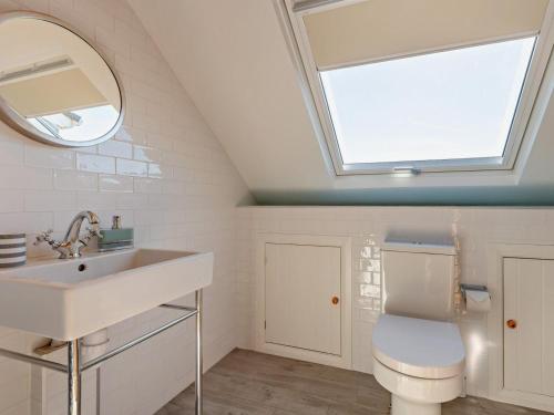 ein Bad mit einem Waschbecken und einem WC mit einem Dachfenster in der Unterkunft 5 Bed in Worth Matravers DC142 in Worth Matravers