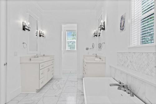 a white bathroom with two sinks and two mirrors at Mermaid Cove in Inlet Beach