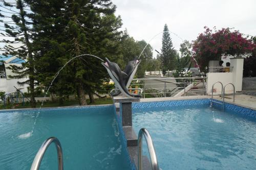 a swimming pool with a statue of a dolphin at WOW Naturefull Resorts in Yercaud