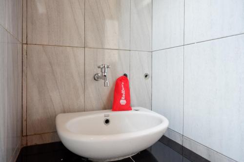 a red bag is sitting on a white sink in a bathroom at RedDoorz @ Kampoeng Etnik Kebumen 2 in Kebumen