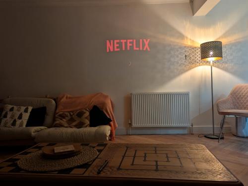 a living room with a couch and a netflix sign on the wall at Newly Refurbished 3 Bed House with 2-Sided Wood Burner and Garden in Edinburgh in Edinburgh