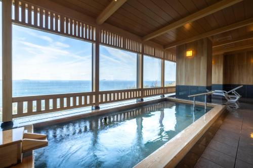 a large indoor swimming pool with large windows at Ijika Daiichi Hotel Kagura in Toba