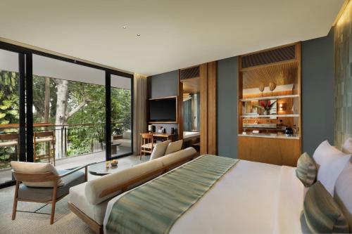a bedroom with a large bed and a living room at Alaya Suites Ubud in Ubud