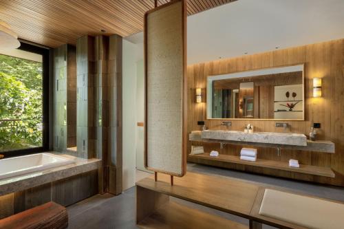 a bathroom with a tub and a sink and a mirror at Alaya Suites Ubud in Ubud