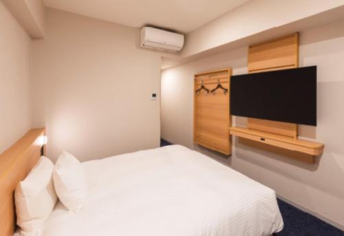 a bedroom with a white bed and a flat screen tv at Sotetsu Grand Fresa Kumamoto in Kumamoto