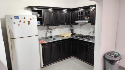 - une cuisine avec des armoires noires et un réfrigérateur blanc dans l'établissement Hermosa casa en Cartago V, à Cartago
