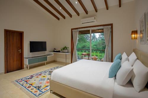 a bedroom with a large bed and a television at Lamrin Morjim Goa in Morjim