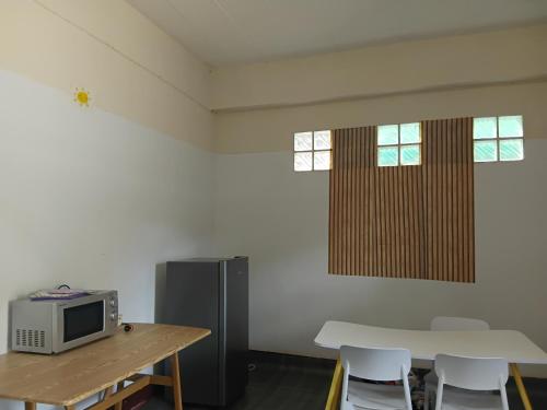 Zimmer mit einem Tisch, einer Mikrowelle, einem Tisch und Stühlen in der Unterkunft Backpack Bay in Nathon Bay