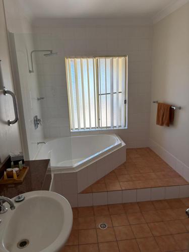 a white bathroom with a tub and a sink at Golden Guitar Motor Inn in Tamworth