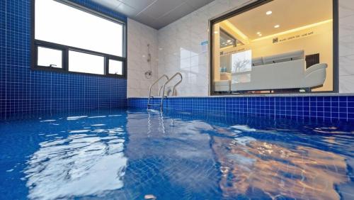 a bathroom with a swimming pool with blue tiles at The Blue 101 Pool Villa in Hajŏng-ni