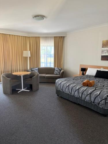 a bedroom with a bed and a couch and a table at Golden Guitar Motor Inn in Tamworth