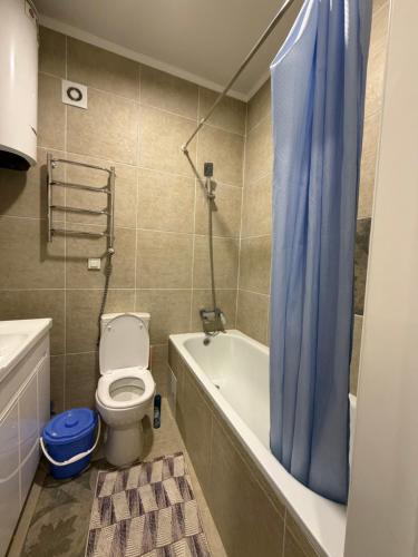 a bathroom with a toilet and a blue shower curtain at Bright & Airy Apartment in Central Bishkek in Bishkek