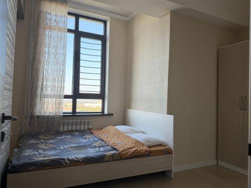 a small bedroom with a bed with a window at Bright & Airy Apartment in Central Bishkek in Bishkek