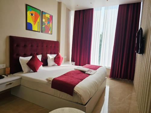 a bedroom with a large bed with a red headboard at Hotel Crystal Sarovar in Mirzāpur