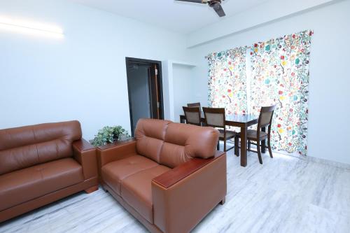 a living room with a couch and a table with chairs at Cozy 2BR in Chennai