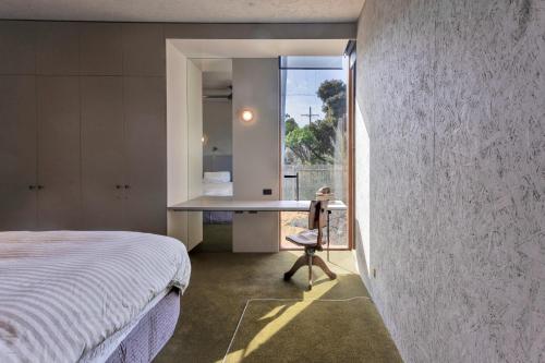 a bedroom with a bed and a desk with a window at The Heads Bath House in Barwon Heads