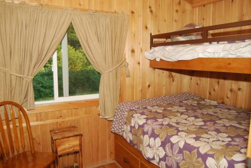 1 Schlafzimmer mit 2 Etagenbetten und einem Fenster in der Unterkunft Seaside Camping Resort Cottage 9 in Seaside