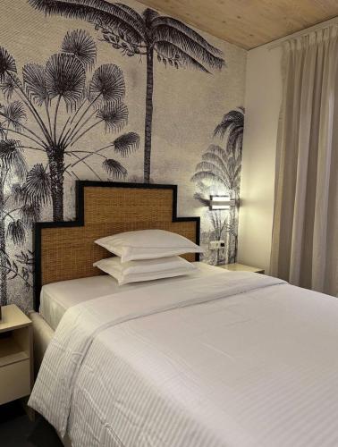 een slaapkamer met een wit bed met palmbomen aan de muur bij A chic apartment by Afra Paje in Paje