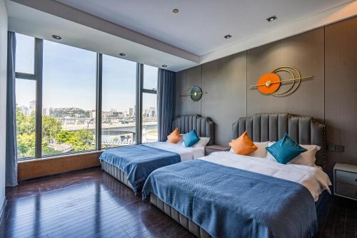 2 bedden in een hotelkamer met grote ramen bij Aixin Yangtze River International Apartment in Chongqing
