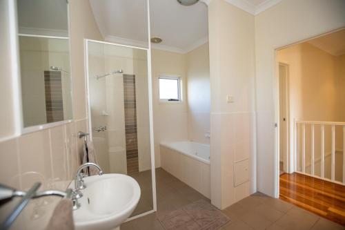 une salle de bain avec un lavabo, une douche et une baignoire dans l'établissement Lofberg Villas, à Muswellbrook