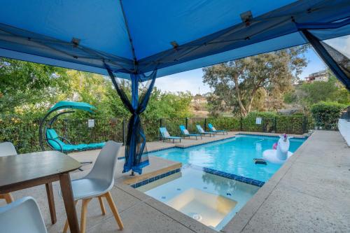a swimming pool with a blue umbrella and chairs at Entire Private Pool, Big Yard, View, 4BR, King Bed, 10 Parking, Available Now in El Cajon