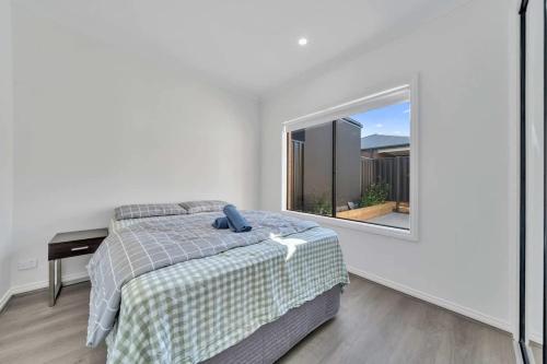 une chambre avec un lit et une grande fenêtre dans l'établissement Modern Family Home Near Kallo Town Centre, à Kalkallo