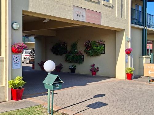 a building with potted plants on the side of it at Golden Guitar Motor Inn in Tamworth